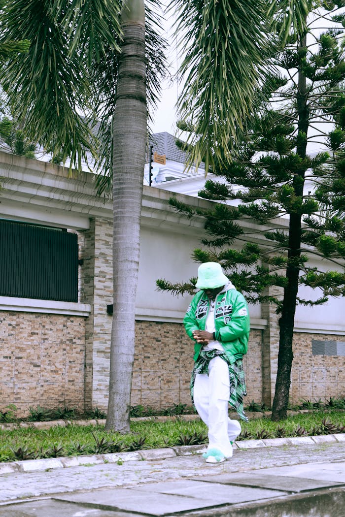 why-choose-us Stylish man in green jacket and hat walking by palm trees in Lagos, Nigeria.