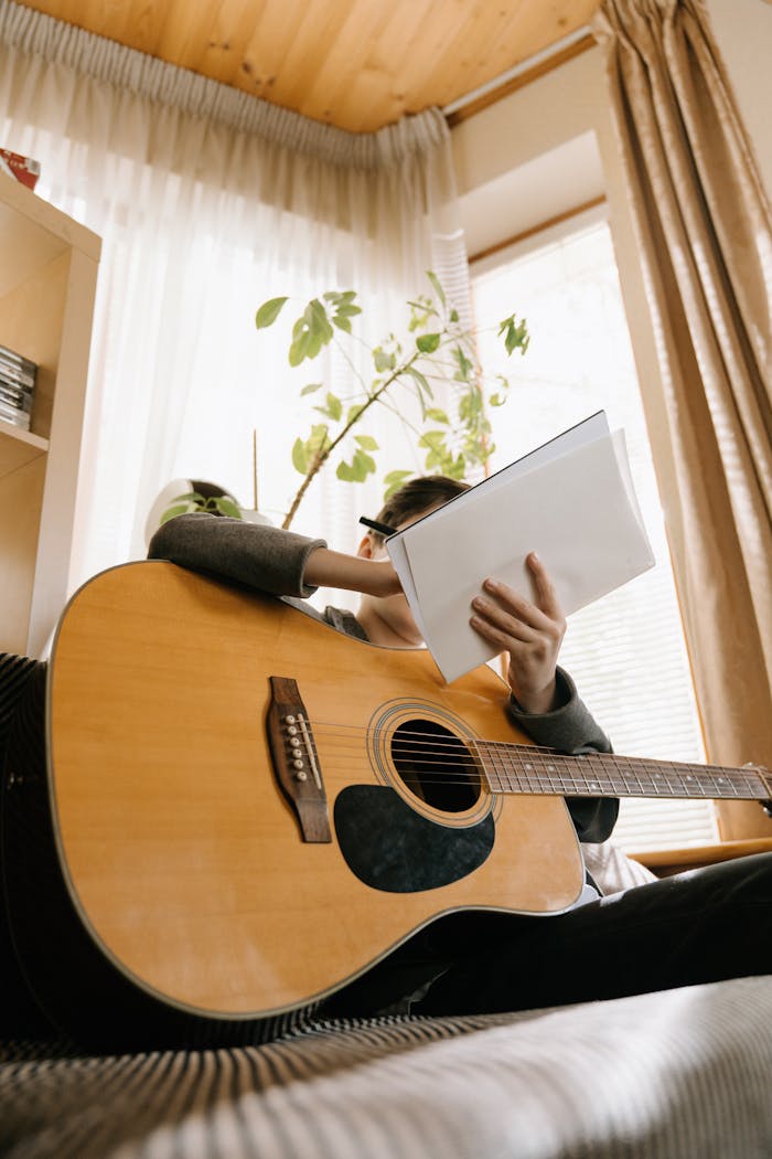 services-02 A young boy playing guitar and writing songs in a cozy indoor setting.